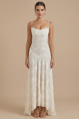 Female model wearing a floral maxi dress with delicate straps on a plain background.