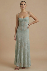 Female model wearing a long floral dress with delicate strap detail on a plain background.