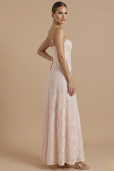 Female model showcasing a floral evening dress with thin straps on a plain background.
